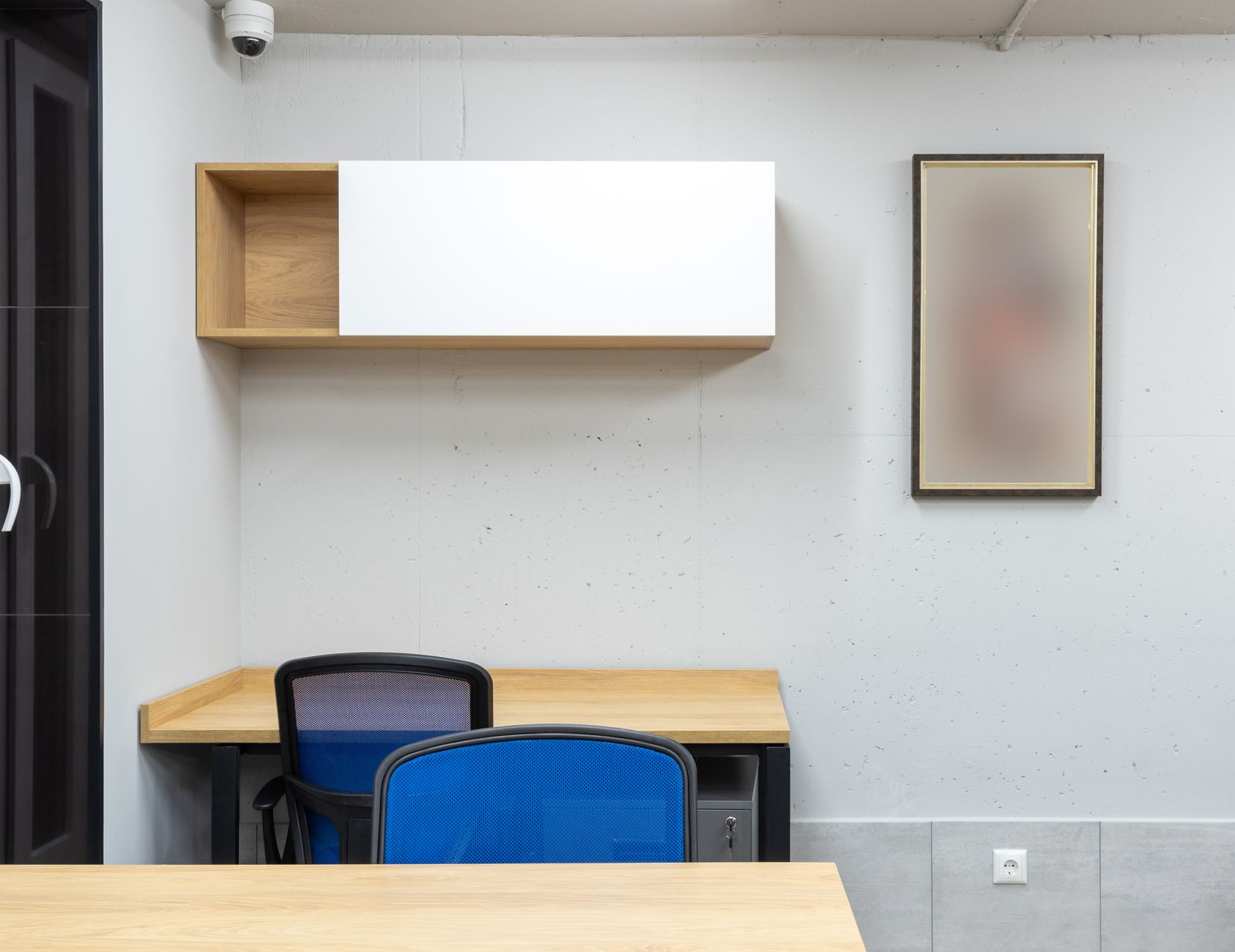 Wooden tables and blue office chairs placed in modern workplace with shelves on wall